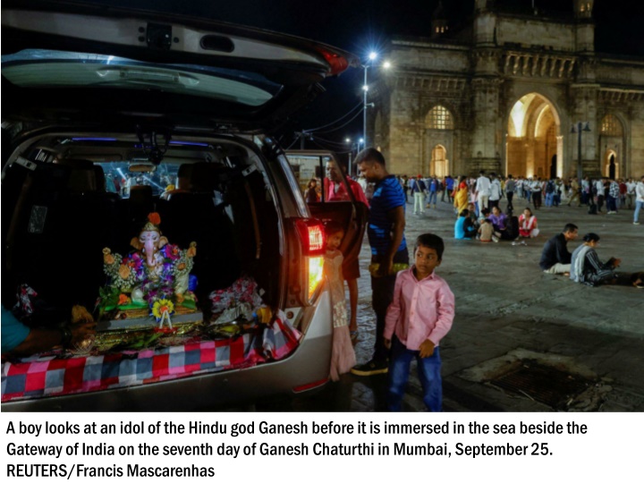 a boy looks at an idol of the hindu god ganesh