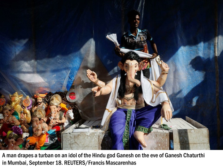 a man drapes a turban on an idol of the hindu