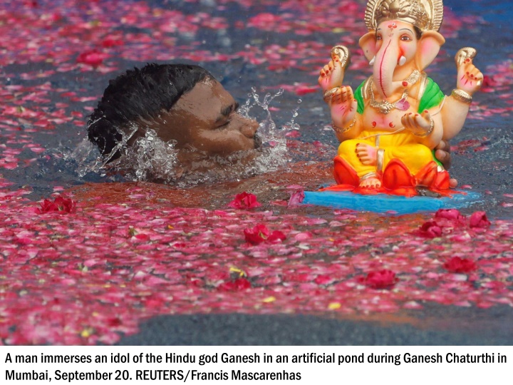 a man immerses an idol of the hindu god ganesh