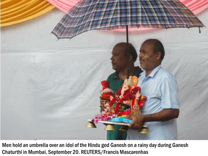 men hold an umbrella over an idol of the hindu