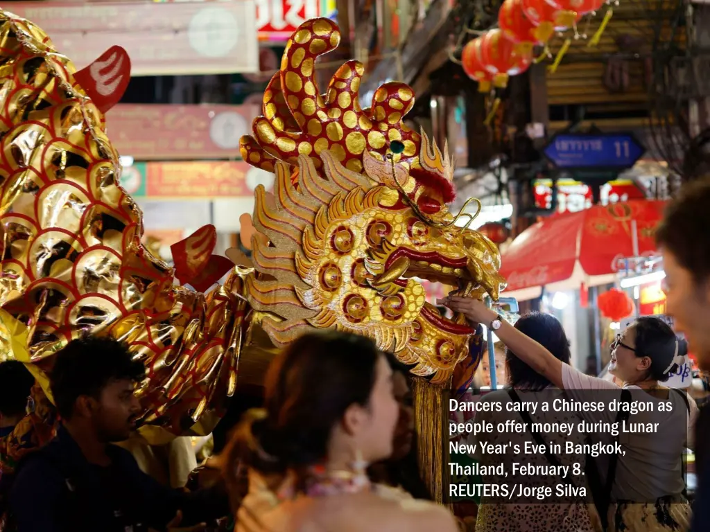 dancers carry a chinese dragon as people offer