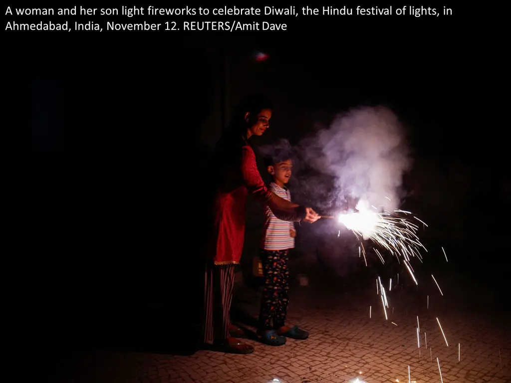 a woman and her son light fireworks to celebrate