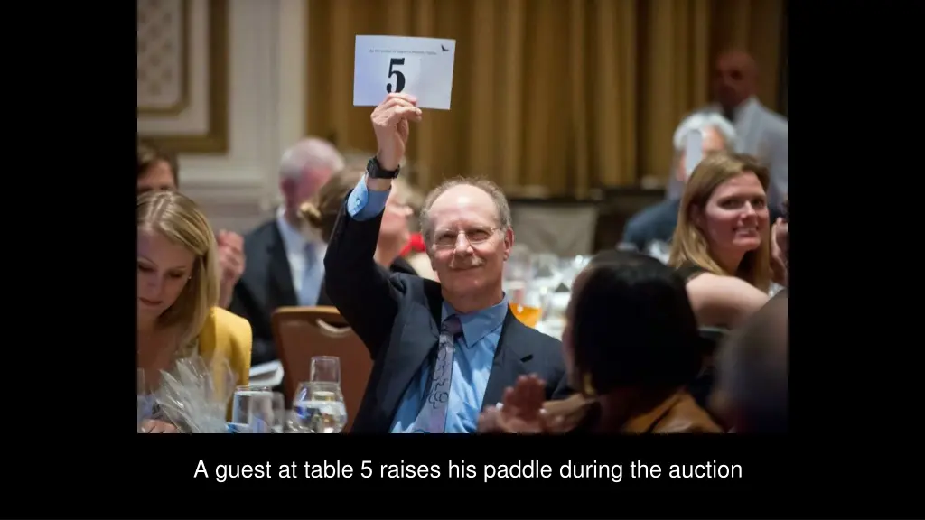 a guest at table 5 raises his paddle during