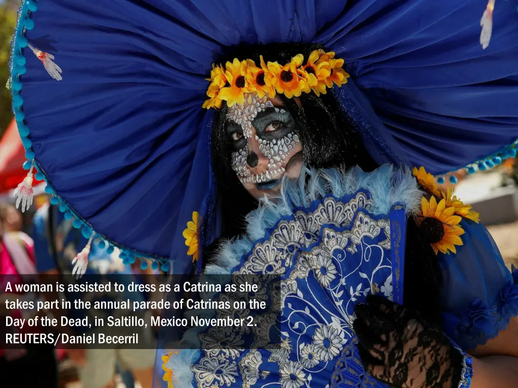 a woman is assisted to dress as a catrina