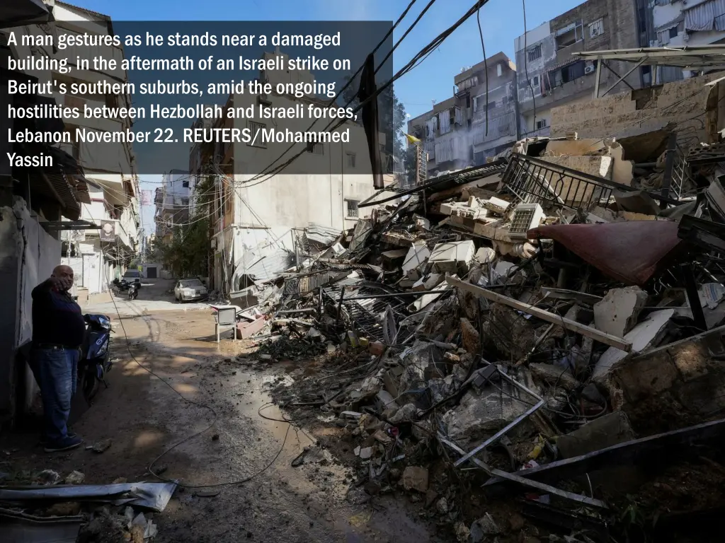 a man gestures as he stands near a damaged