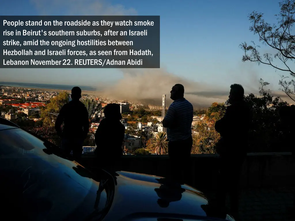 people stand on the roadside as they watch smoke