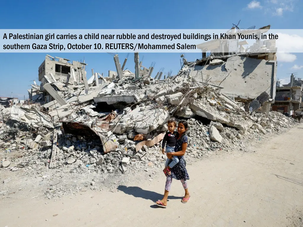 a palestinian girl carries a child near rubble