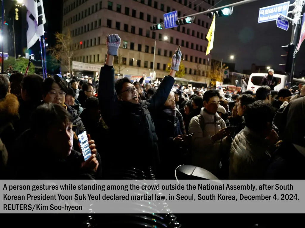 a person gestures while standing among the crowd