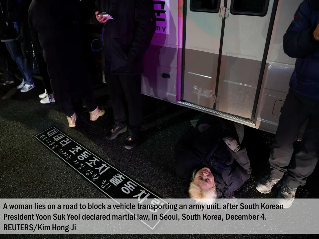 a woman lies on a road to block a vehicle