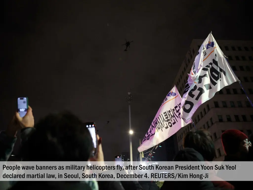 people wave banners as military helicopters