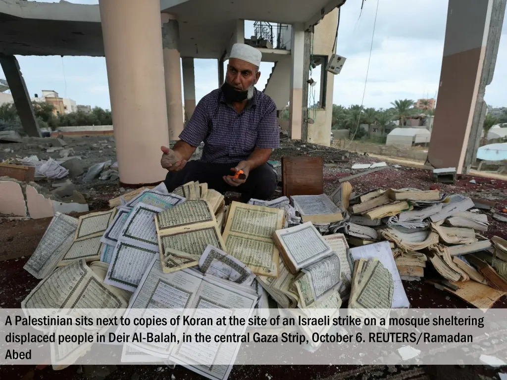 a palestinian sits next to copies of koran