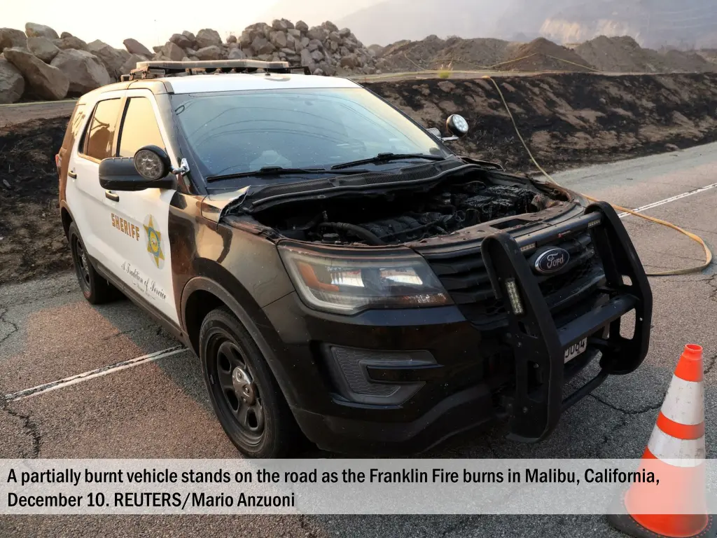 a partially burnt vehicle stands on the road