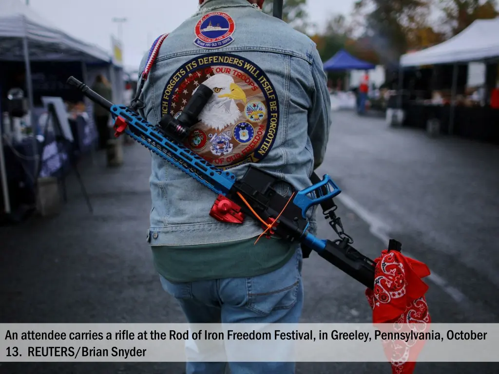 an attendee carries a rifle at the rod of iron