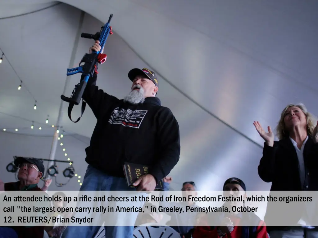 an attendee holds up a rifle and cheers