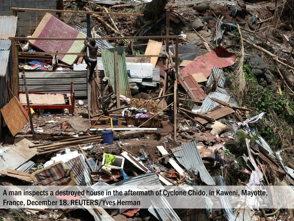 a man inspects a destroyed house in the aftermath