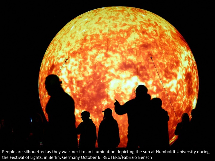 people are silhouetted as they walk next