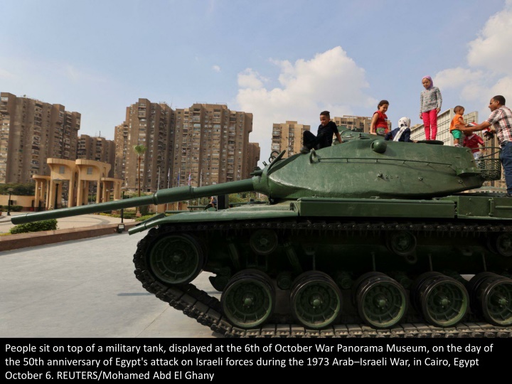 people sit on top of a military tank displayed